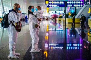 Travelers in protective suits are seen at Wuhan Tianhe International Airport in Wuhan